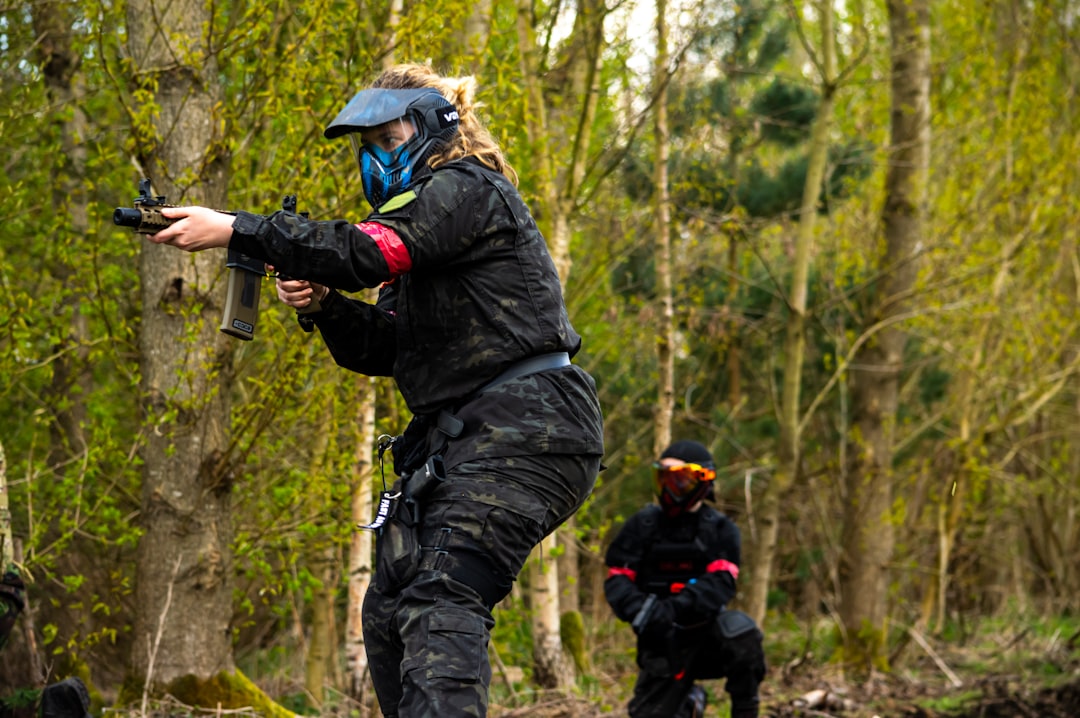 Emocjonująca rozgrywka paintballowa – zawodnik w pełnym biegu na polu pełnym drewnianych osłon.